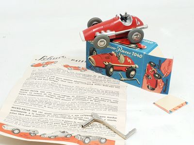 a red toy car sitting on top of a piece of paper next to a pair of scissors