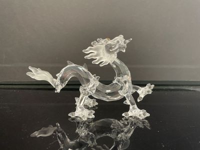 une figurine en verre représentant un dragon posé sur une table