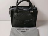 le petit sac noir est posé à côté d'un tissu gris