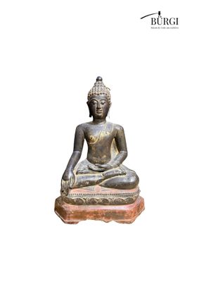 statue of a seated buddha sitting on a stone base
