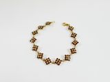 un bracelet en or orné de perles marron sur un fond blanc