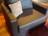 une chaise noire avec un coussin dessus, dans un salon
