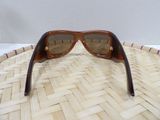 brown sunglasses on a woven basket with a white wall in the background