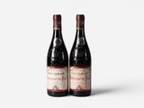 two bottles of red wine sitting next to each other on a white surface
