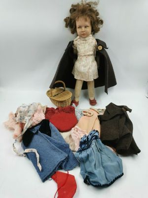 une poupée qui se tient à côté d'un tas de vêtements