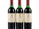 three bottles of red wine sitting next to each other on a white surface