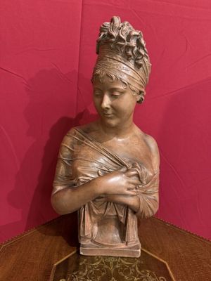 statue en bronze représentant une femme tenant un panier posé sur une table en bois
