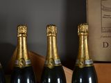 four bottles of champagne are lined up on a shelf