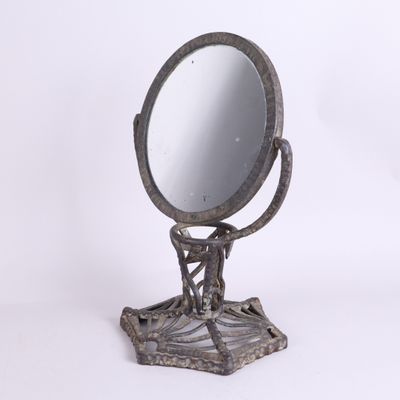 un petit miroir en métal posé sur un support, sur fond blanc