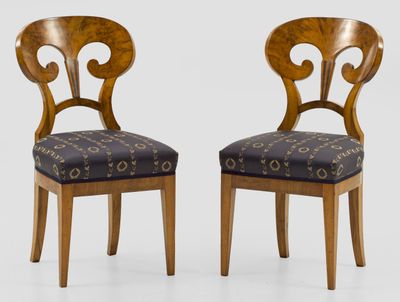 deux chaises en bois dont les assises sont recouvertes d'un tissu à motifs sur fond blanc
