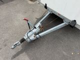 a white trailer with a red handle attached to the side of it
