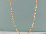 un collier à chaîne en or posé sur une surface en marbre