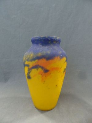 un vase jaune et bleu posé sur une surface blanche, avec un arrière-plan gris