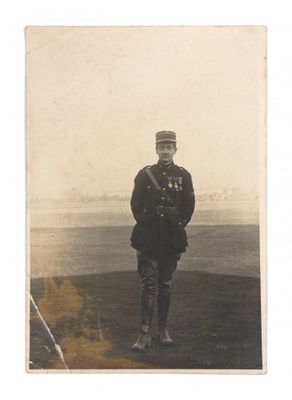 an old photo of a man in uniform standing in a field