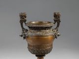 une urne antique en bronze à deux anses, posée sur un socle en marbre