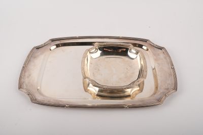 un plateau en argent muni d'une poignée en argent, posé sur une table blanche