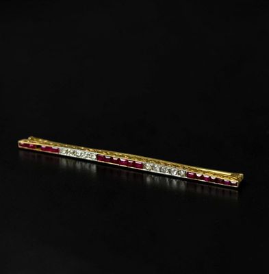 a gold and ruby bar brooch with diamonds