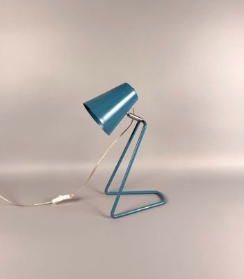 une image représentant une lampe de table bleue posée sur une surface blanche