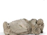 an old statue of a person laying down on a white surface