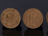 quatre pièces d'or sont alignées sur une surface noire