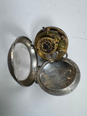 une petite montre de poche en argent avec une horloge à l'intérieur