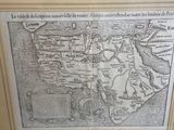 an old map of the world in a gold frame on a table