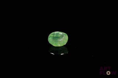 a close up of a green gemstone on a black surface