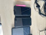 several cell phones are lined up on a table next to a phone charger