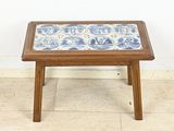 une petite table en bois sur laquelle est posé un carreau bleu et blanc