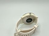 a close up of a watch with a white band on a white surface