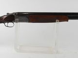 un fusil de chasse posé sur un socle transparent, devant un fond blanc