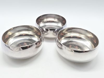 three silver bowls sitting on top of each other on a white surface