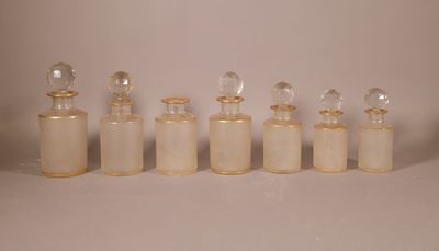 six petites bouteilles en verre sont alignées sur une surface blanche