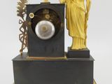 a gold statue next to a black clock on a stand