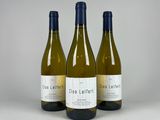 three bottles of white wine sitting next to each other on a table