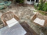 two wicker chairs and a table in the backyard
