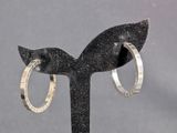 pair of silver hoop earrings on a black stand against a gray background