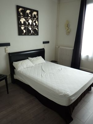 un lit avec des draps blancs et une tête de lit noire dans une chambre