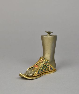 an image of a gold shoe shaped candle holder on a gray surface