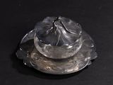 a silver plate with a bowl on it on a black surface