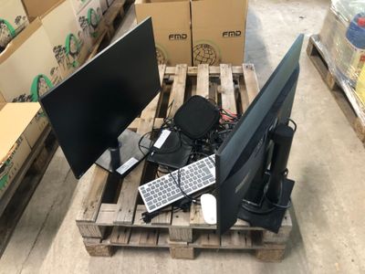 deux écrans et un clavier posés sur une palette dans un entrepôt