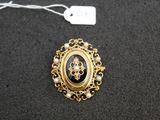 a close up of a black and gold broochle with pearls