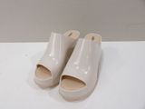 une paire de sabots blancs posés sur une table blanche, sur fond blanc