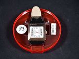 a watch sitting on a red plate with a price tag