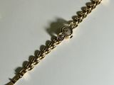 gold tone bracelet with clear crystal stones on a white surface