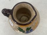 a small vase with a handle sitting on a table