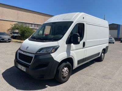 Une camionnette blanche est garée sur un parking près d'un immeuble.