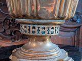 a silver vase sitting on top of a table next to a chair