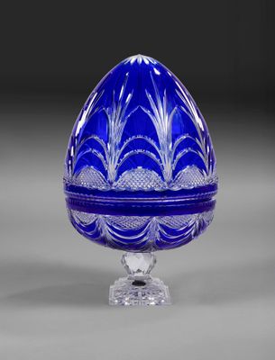 un œuf en verre bleu posé sur un socle