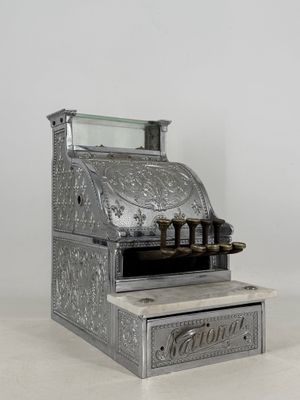 an old fashioned cash register sitting on top of a white counter